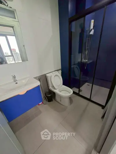 Modern bathroom with sleek design and glass shower enclosure in urban apartment.