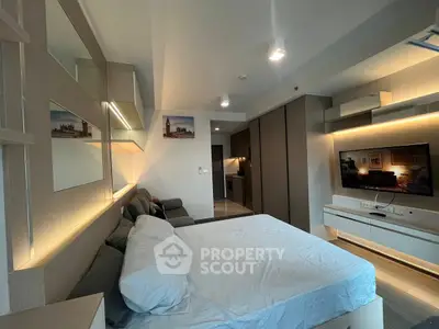 Modern studio apartment with stylish decor and ambient lighting, featuring a cozy bed and sleek entertainment unit.