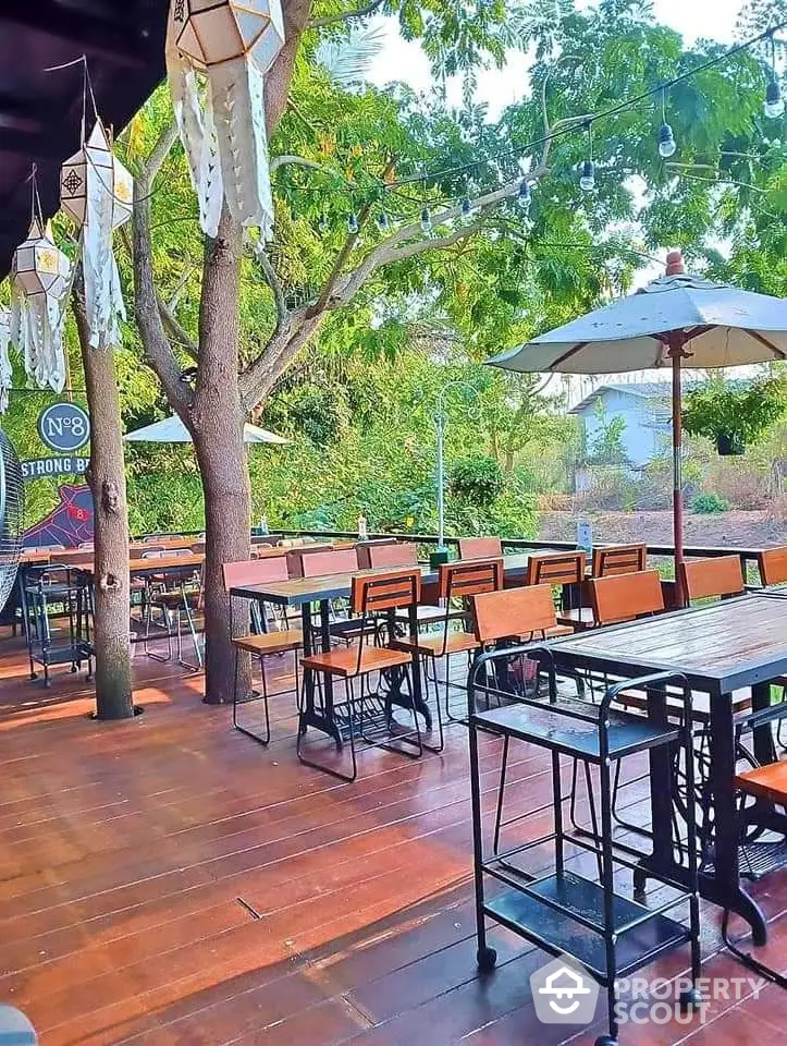 Charming outdoor patio with wooden deck and stylish seating under lush trees, perfect for relaxation.