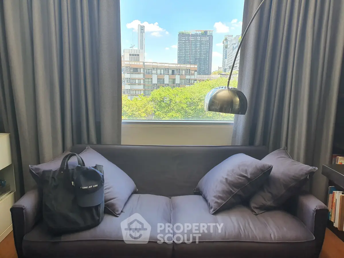 Stylish living room with modern sofa and city view through large window, perfect for urban living.