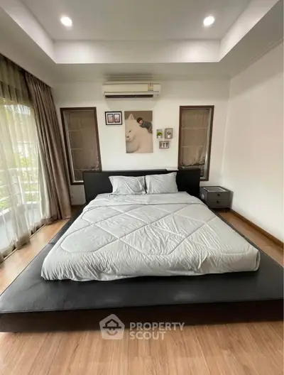 Spacious bedroom with modern decor and large windows for natural light.