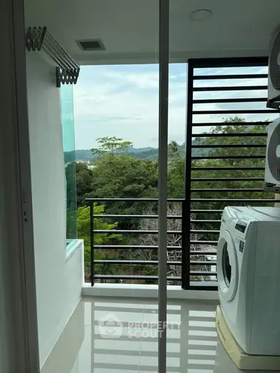 Modern balcony with washing machine and scenic view of lush greenery.