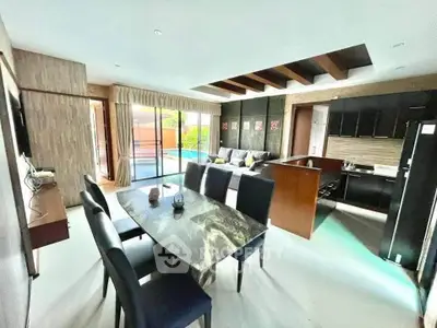 Luxurious open-plan living room with pool view, elegant dining area, and modern kitchen in a stylish home.