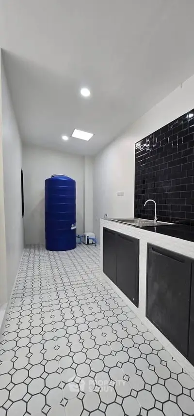 Modern utility room with sleek black backsplash and large blue water tank.