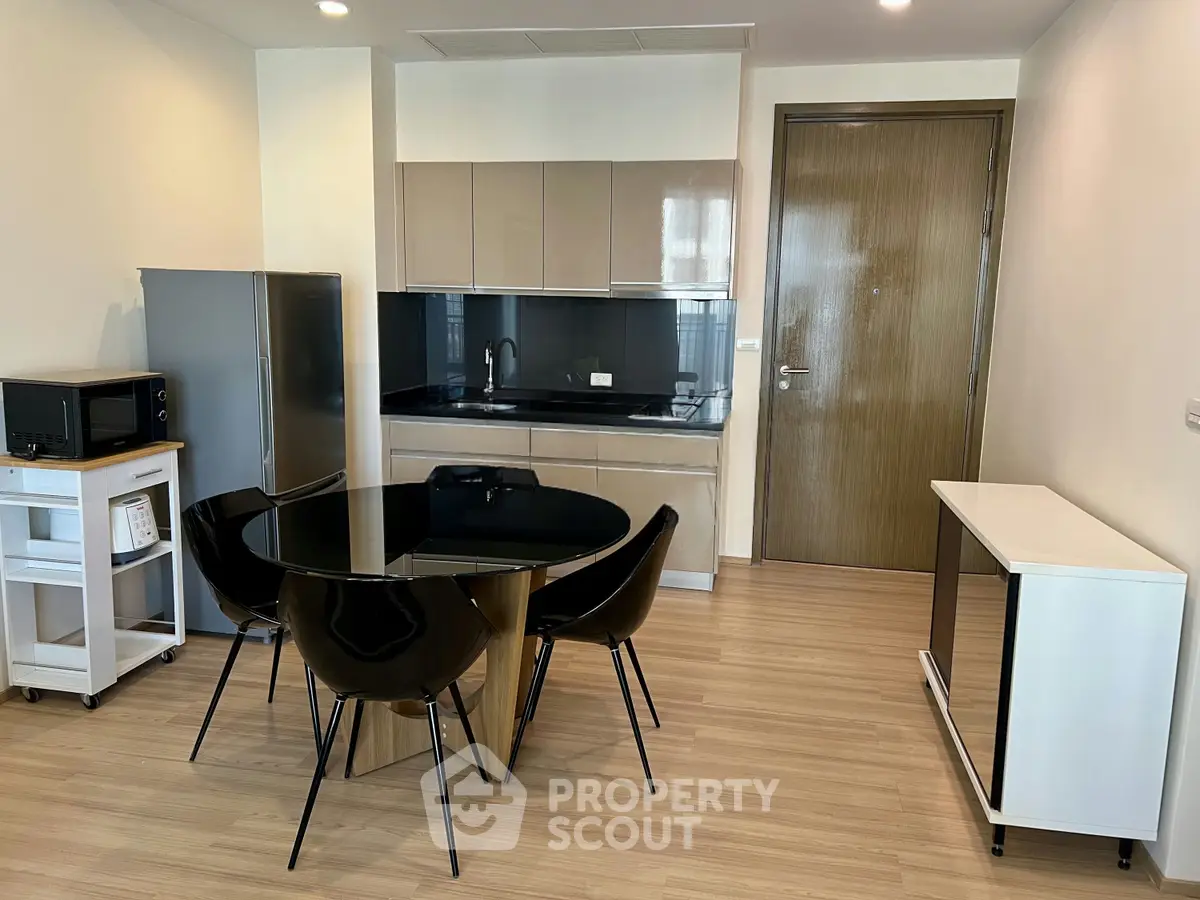 Modern kitchen with sleek black dining set and stainless steel appliances in a stylish apartment.