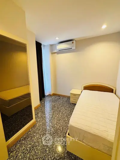 Cozy bedroom with air conditioning and mirrored wardrobe in modern apartment.