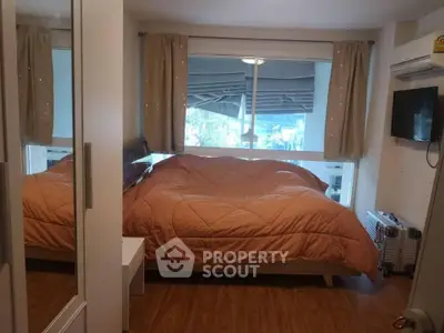 Cozy bedroom with large window and modern amenities, perfect for relaxation and comfort.