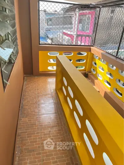 Charming balcony with vibrant yellow railing and tiled floor, perfect for relaxing outdoors.