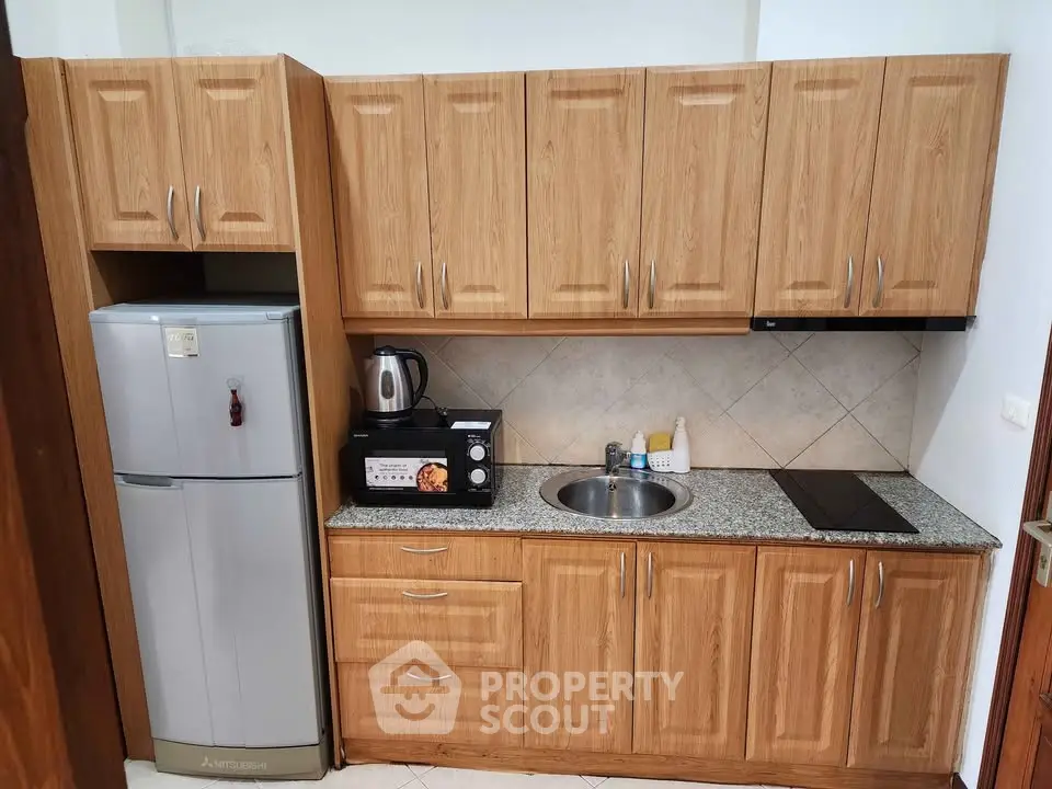 Compact kitchen with wooden cabinets, granite countertop, and modern appliances.