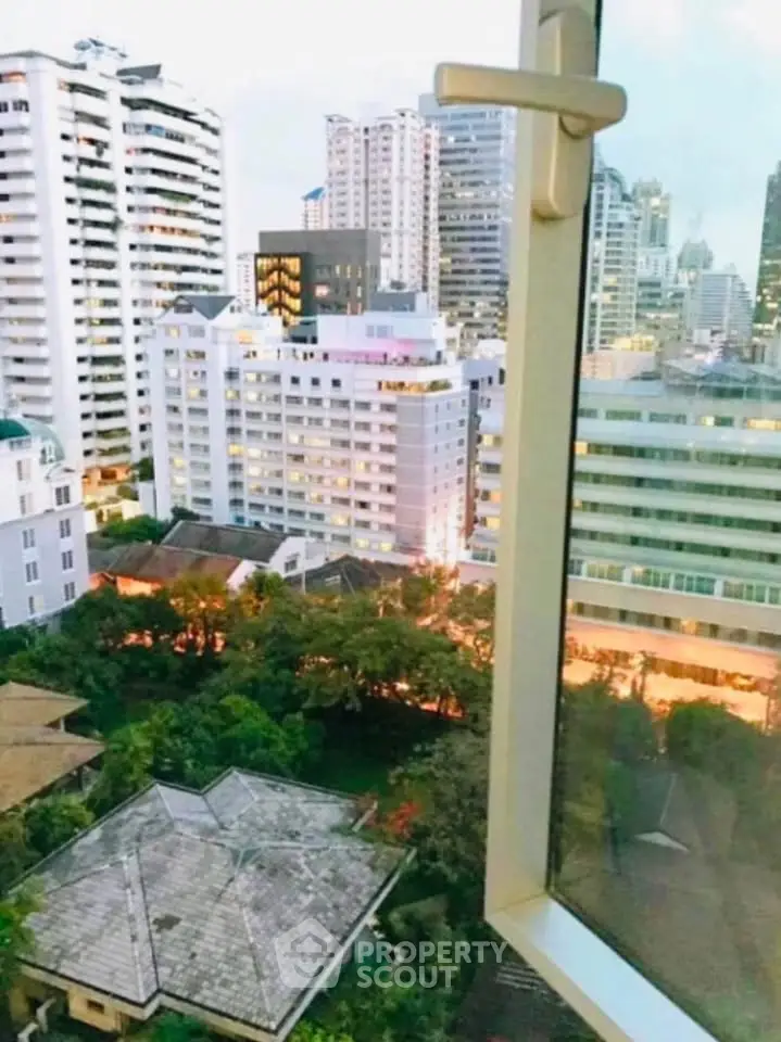 Stunning cityscape view from a high-rise window overlooking urban skyline and lush greenery.