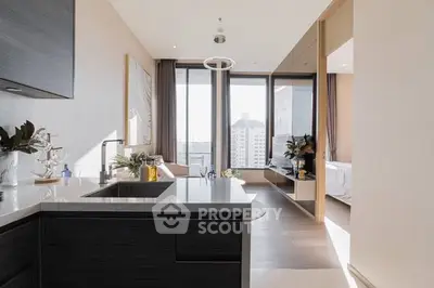 Modern open-layout kitchen with sleek design and city view, adjacent to a bright bedroom.