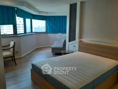 Spacious bedroom with large windows and modern furnishings in a high-rise apartment.