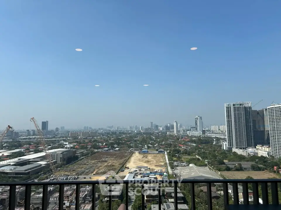 Stunning cityscape view from a high-rise balcony, showcasing urban skyline and construction cranes.