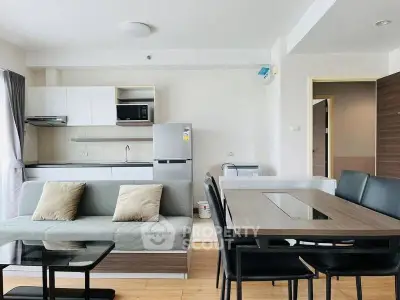 Modern open-plan living room with sleek kitchen and dining area, featuring contemporary furniture and appliances.