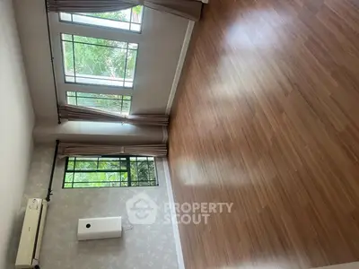 Spacious empty room with large windows and wooden flooring, perfect for customization.