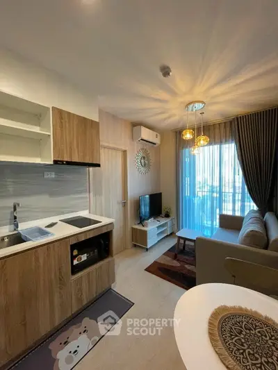 Modern living room with open kitchen, stylish decor, and natural light from large windows.