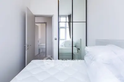 Modern minimalist bedroom with mirrored wardrobe and plush bedding