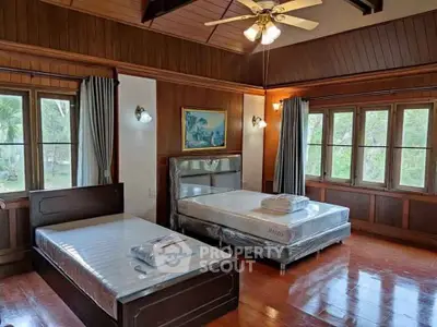Spacious bedroom with wooden accents and large windows offering serene garden views.