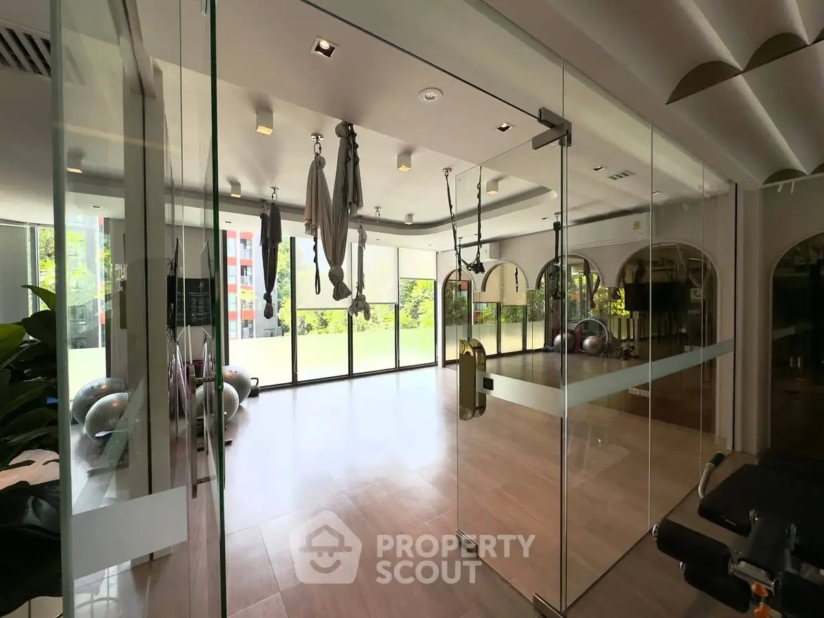 Modern gym with glass walls and aerial yoga setup in luxury apartment building.