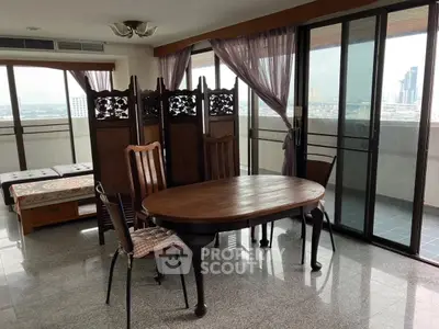 Spacious living room with elegant wooden furniture and large windows offering city views.