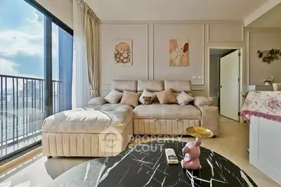Spacious living room with plush sofa and city view balcony, perfect for relaxation.