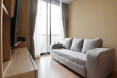 Modern living room with cozy gray sofa and large window offering natural light.
