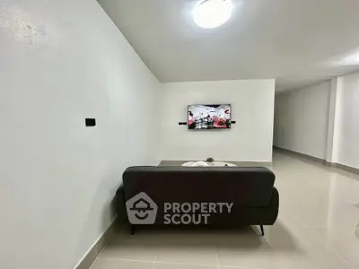 Minimalist living room with sleek black sofa and wall-mounted TV