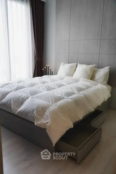 Modern bedroom with stylish bed and natural light, featuring sleek storage drawers and elegant decor.