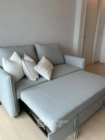 Modern living room with stylish gray sofa bed and decorative pillows.