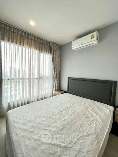 Modern bedroom with large window and air conditioning in a stylish apartment.