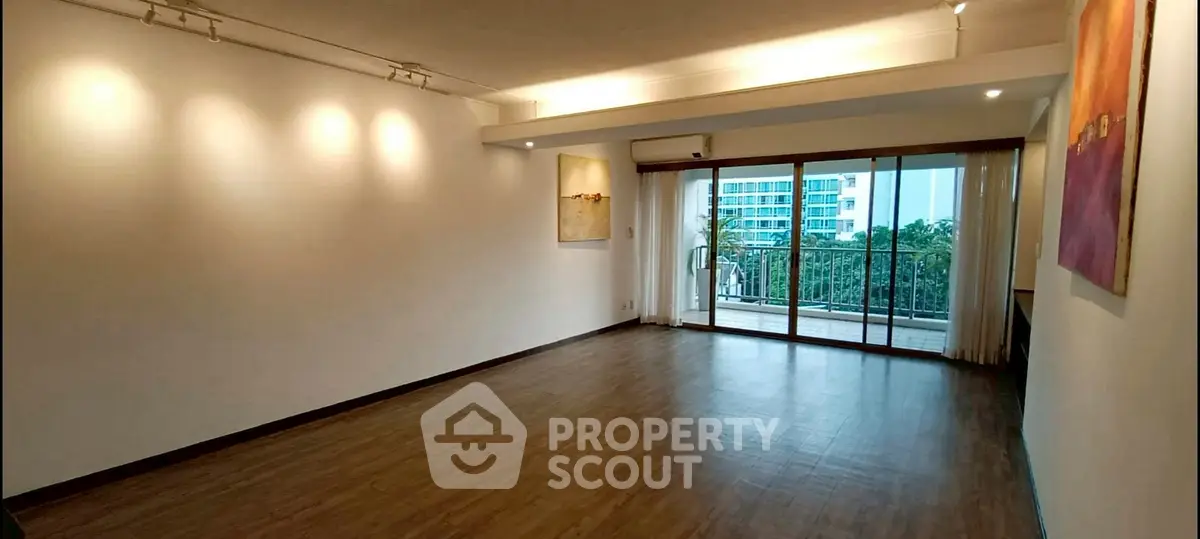 Spacious living room with large windows and balcony access in modern apartment.