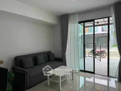Modern living room with sleek sofa and glass doors leading to outdoor area, perfect for relaxation.