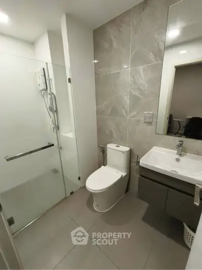 Modern bathroom with glass shower and sleek fixtures in contemporary apartment.