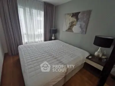 Cozy bedroom with large bed and elegant decor, featuring soft lighting and modern artwork.