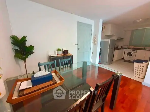 Charming dining area with glass table and modern kitchen featuring stainless steel appliances.