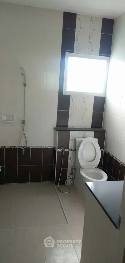 Modern bathroom with sleek design and natural light, featuring a shower and toilet.