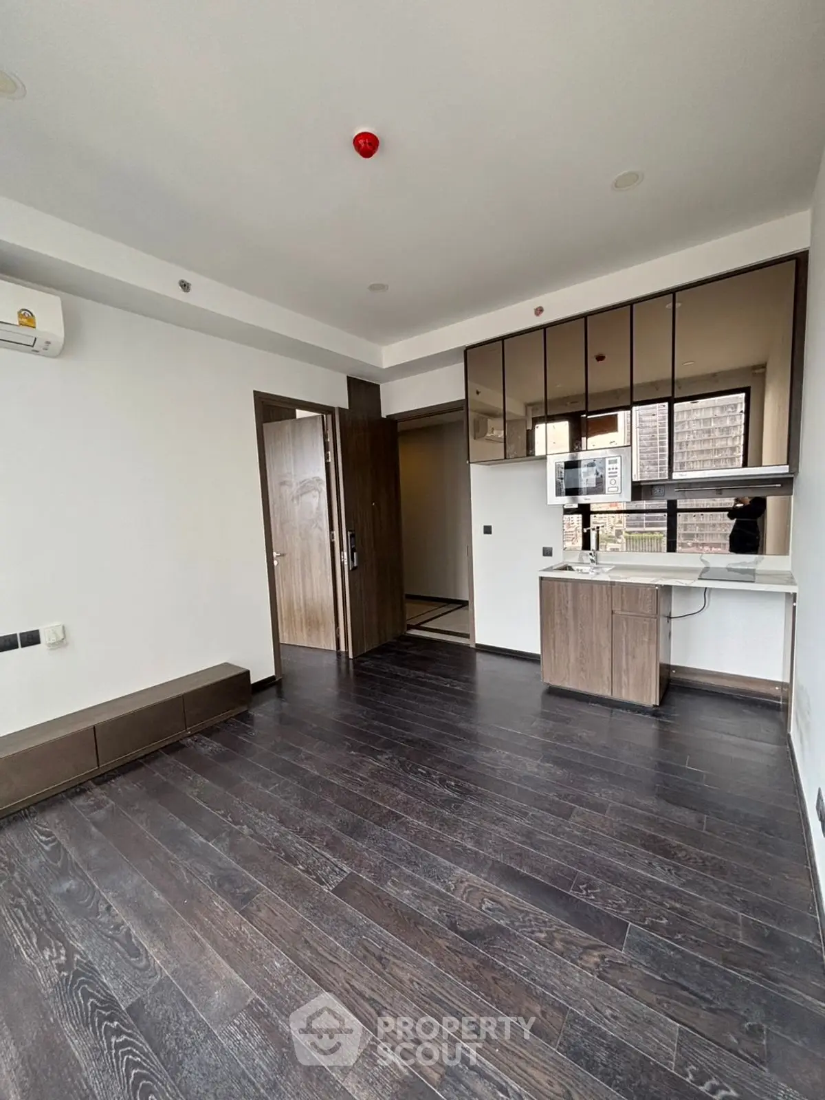 Modern apartment interior with dark wood flooring and compact kitchen area.