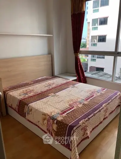 Cozy bedroom with large window and stylish bedding in modern apartment.