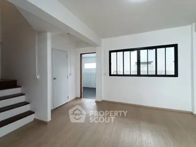 Spacious modern interior with wooden flooring and large window, ideal for customization.