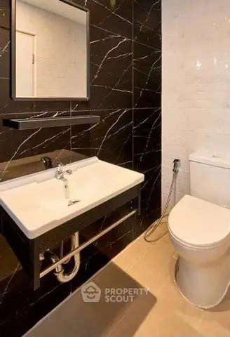 Modern bathroom with sleek black marble tiles and contemporary fixtures.