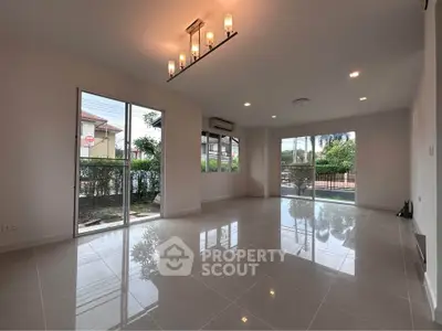 Spacious modern living room with large windows and elegant lighting, perfect for natural light and comfort.