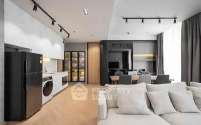 Modern open-plan living room with sleek kitchen and dining area, featuring stylish lighting and contemporary design.