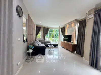Spacious modern living room with elegant decor and large windows offering garden views.