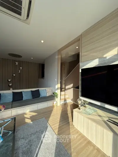Modern living room with sleek design, large TV, and stylish lighting