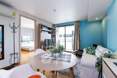 Modern living room with vibrant blue accent wall and cozy furnishings in a stylish apartment.