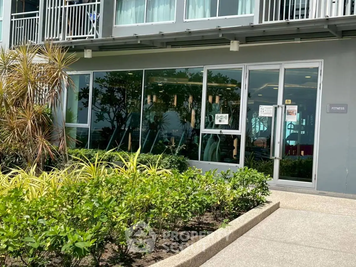 Modern fitness center exterior with lush greenery and glass facade