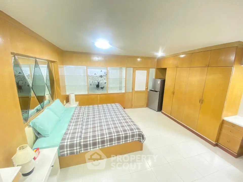 Spacious bedroom with built-in wooden wardrobes and cozy bed in modern apartment.
