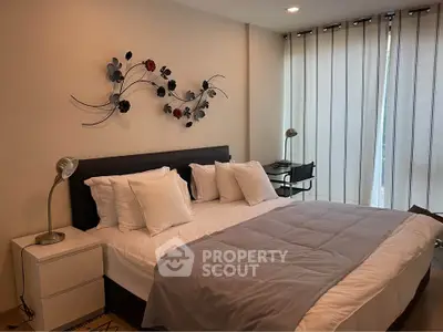 Elegant bedroom with modern decor and natural light, featuring a comfortable bed and stylish wall art.