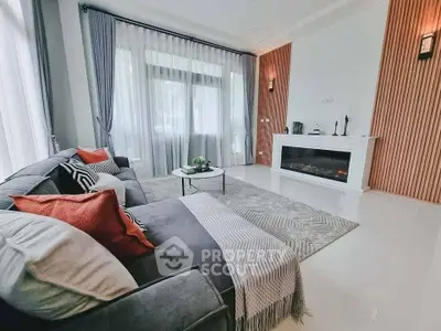Elegant living room with modern decor, cozy gray sofa, stylish fireplace, and large windows for natural light.