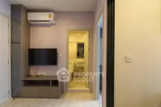 Modern apartment interior with wall-mounted TV and air conditioning, leading to a compact bathroom.